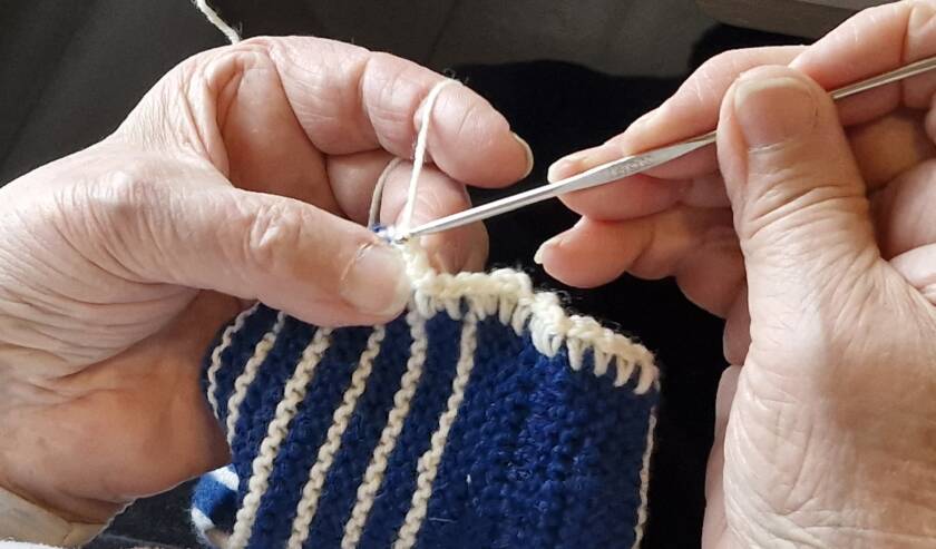 Patalapun reunusta virkkaavat kädet.