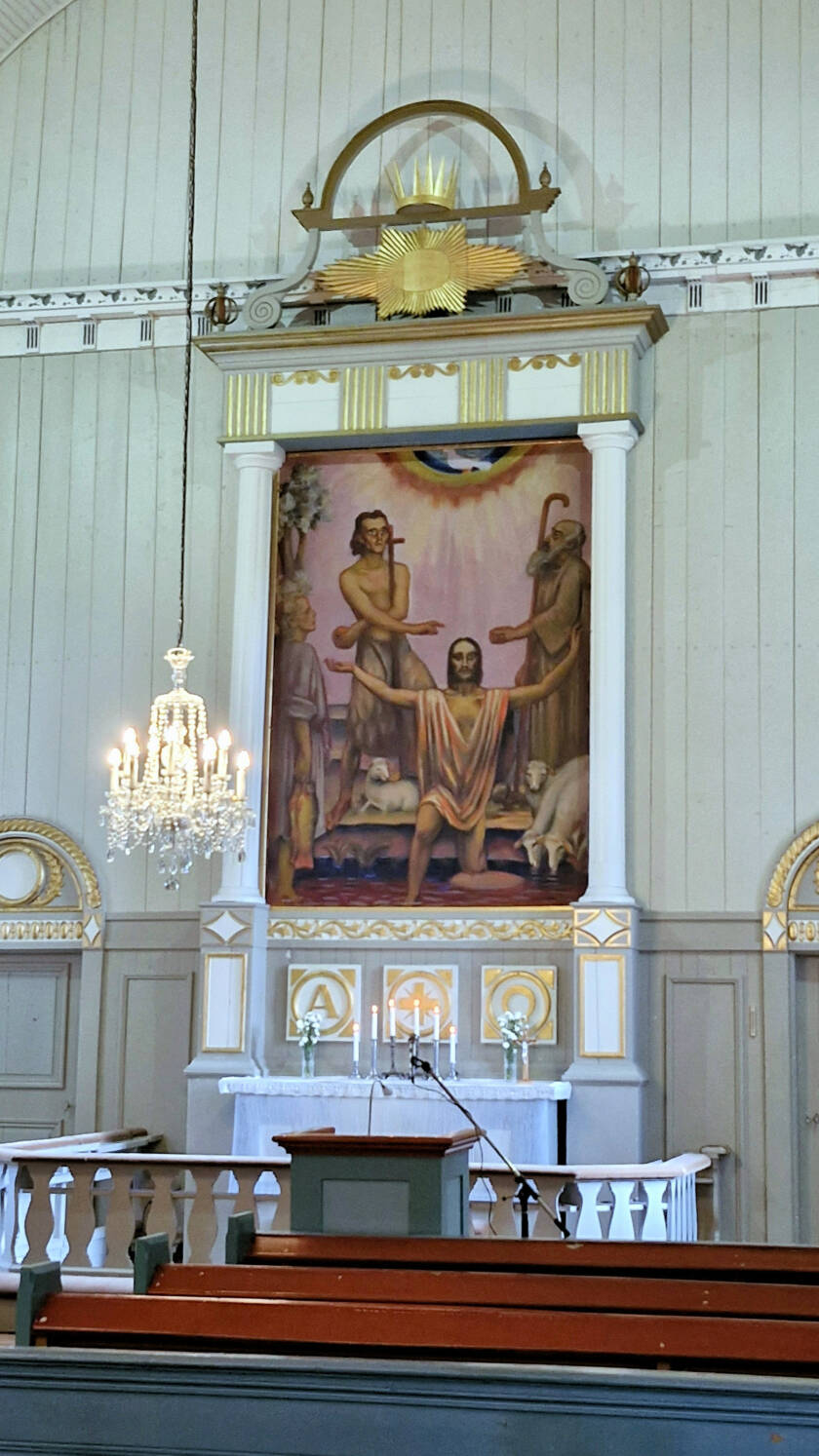 Kirkon alttaritaulu, pöydällä taulun alla palamassa kuusi kynttilää.