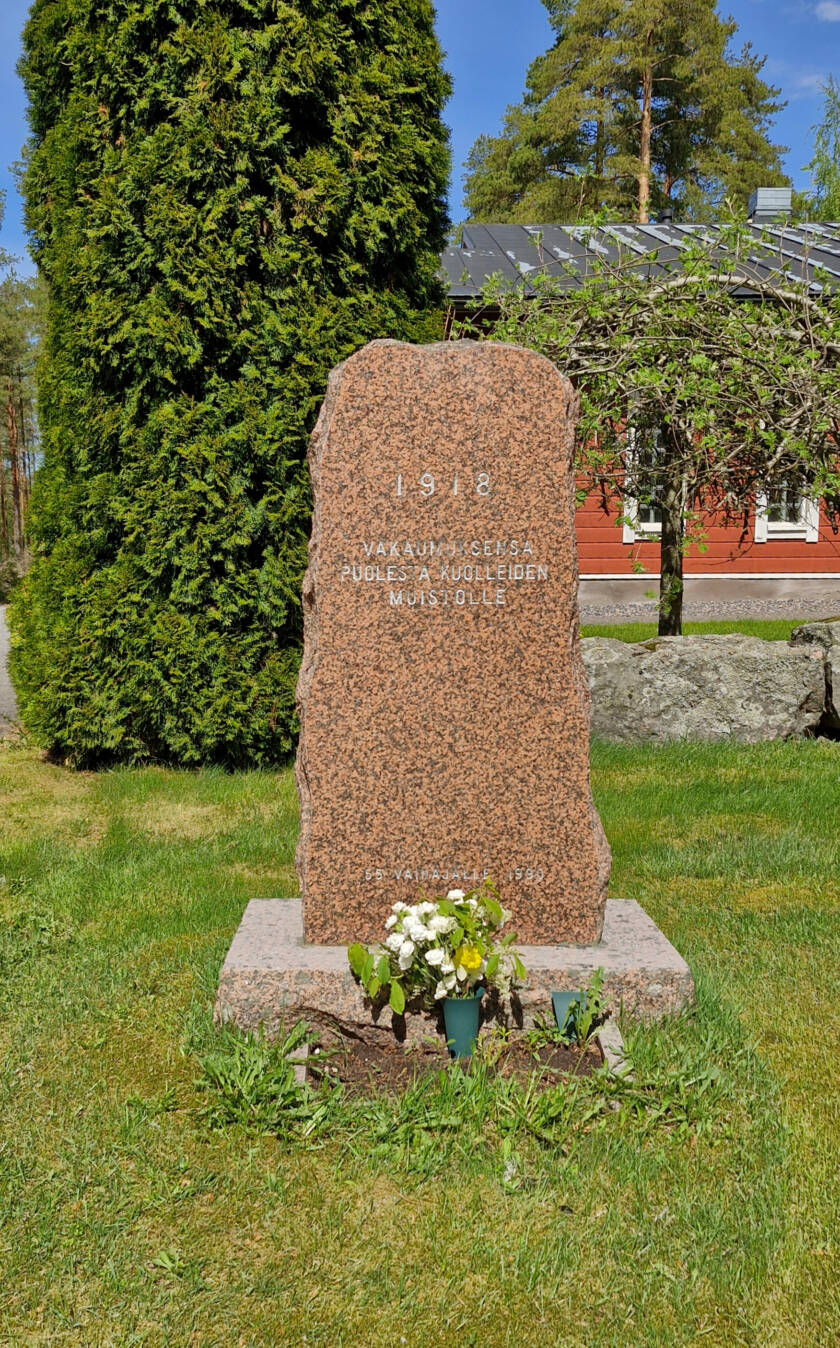 Kivipaasi rosoisin reunoin, kukkia juurella.