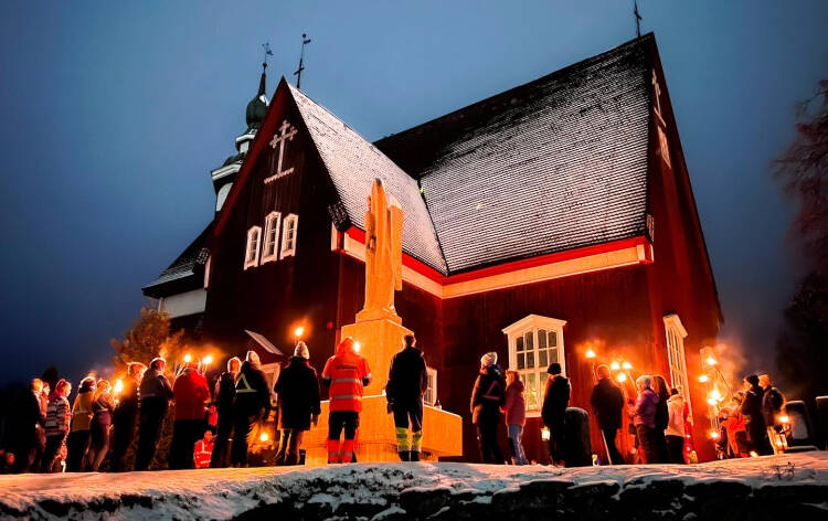 Kuvassa Yläneen kirkko iltapimeässä sekä soihtukulkue.