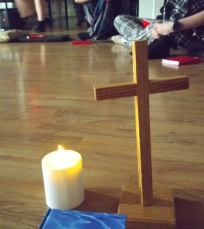 Risti, kynttilä ja Raamattu lattialla.