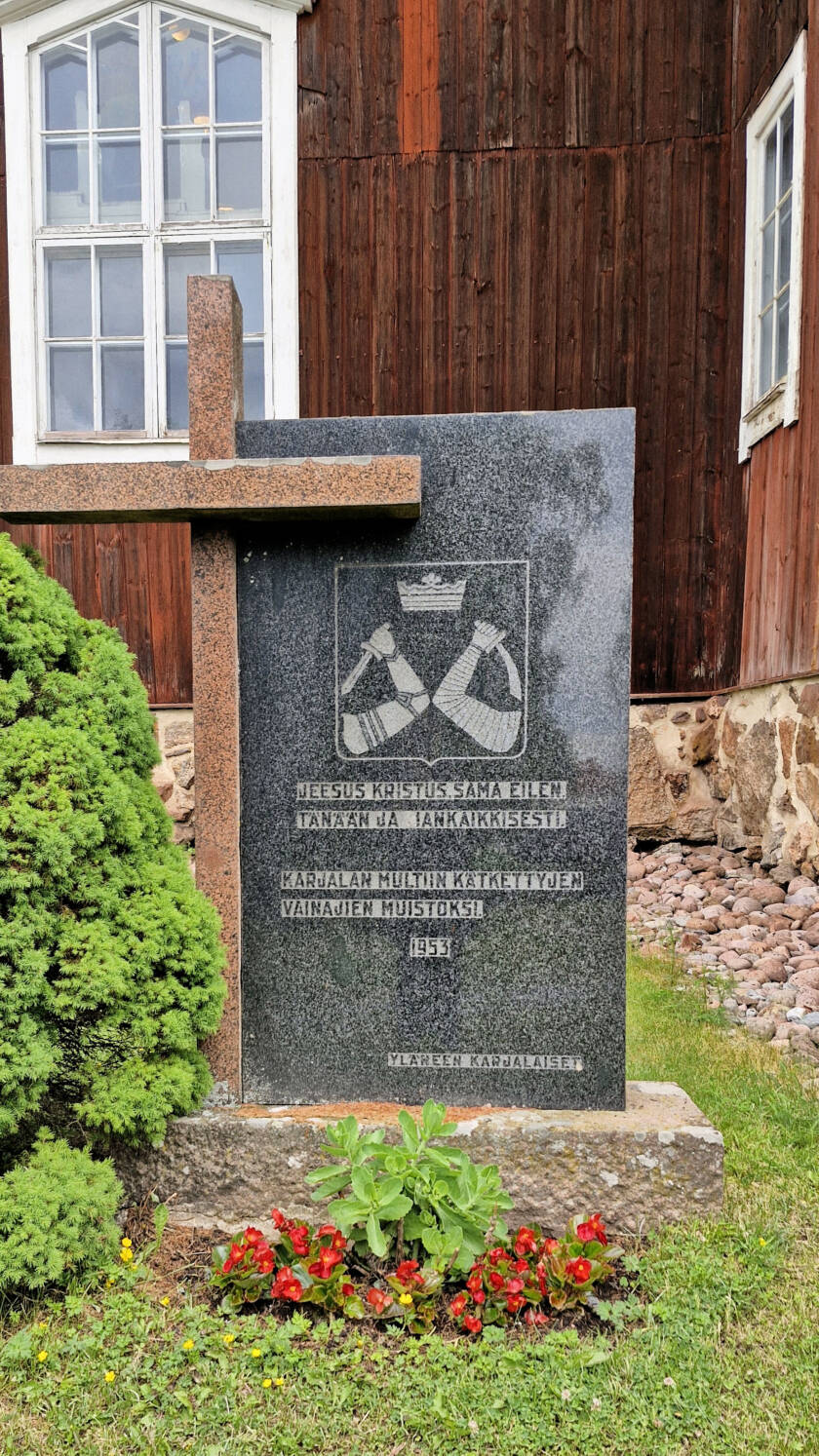 Korkea muistokivi, jonka reunustalla kiveä korkeampi risti.
