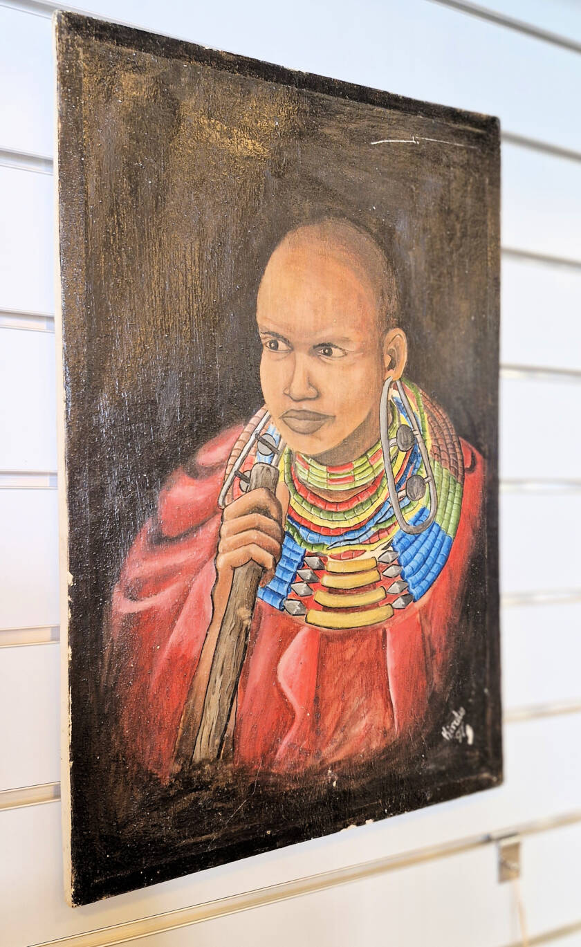Taulussa maasai kaulassaan leveitä helmikoruja ja kädessään paimensauva.
