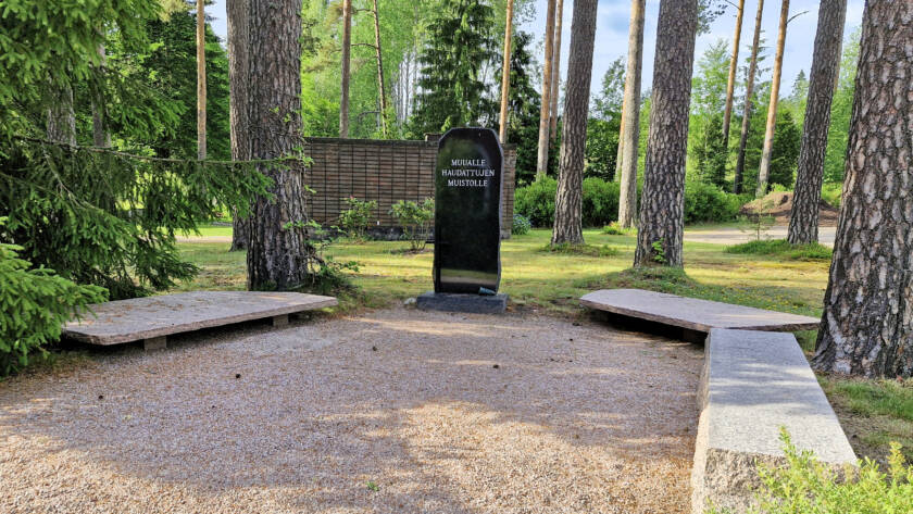 Keskellä korkea muistopaasi, jonka kummallakin sivulla laakea kivilaatta.