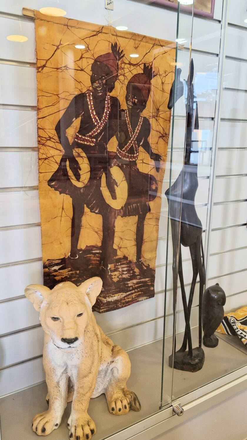 Leijonapatsas, puinen kirahvipatsas, kangas jossa kaksi tansanialaista soittaa rumpuja seisaaltaan.